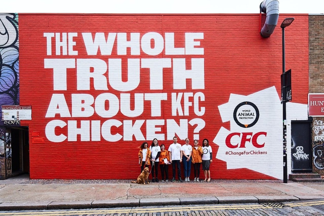 world_animal_protection_uk_team_standing_next_to_cfc_mural_advert_in_london