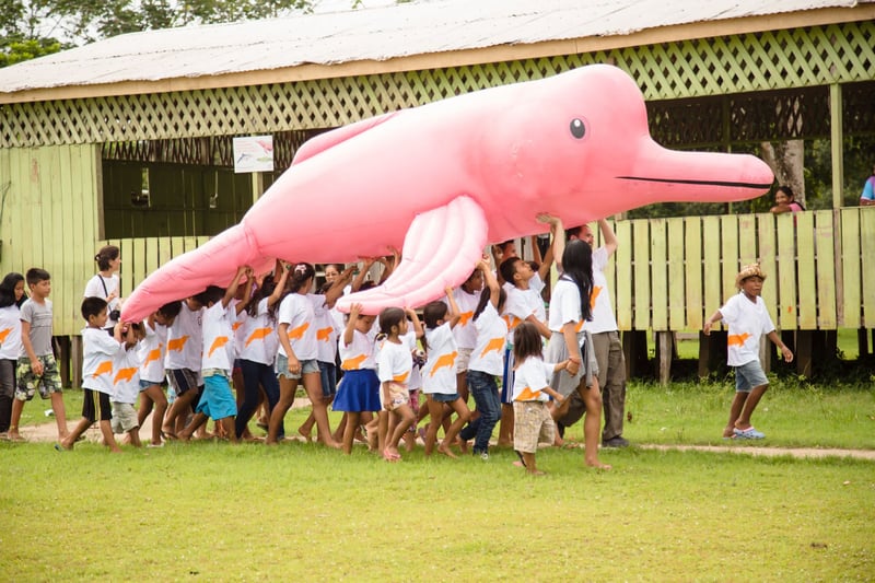 Children in a Brazilian Amazon community carrying an inflatable pink river boto dolphin - World Animal Protection
