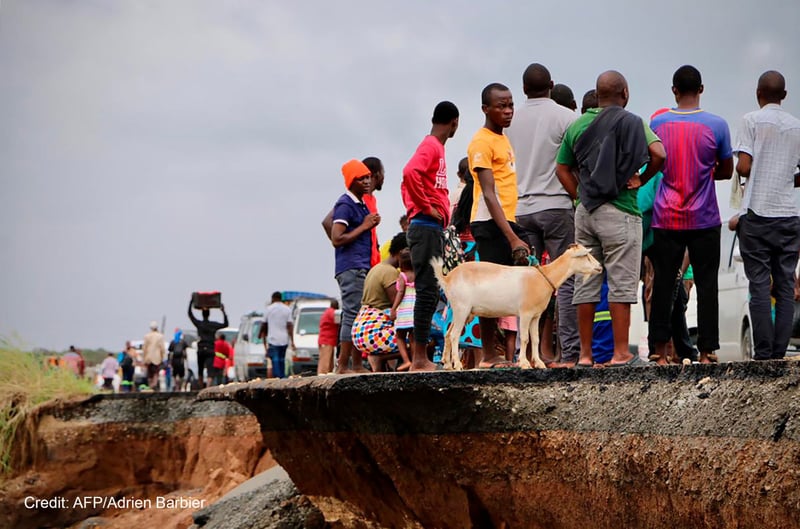 Locals beside cyclone damaged road. Credit: AFP/Adrien Barbier